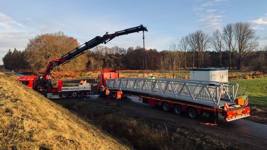 Aluminium bridge span loaded on a low-loader trailer with a crane truck at the delivery site