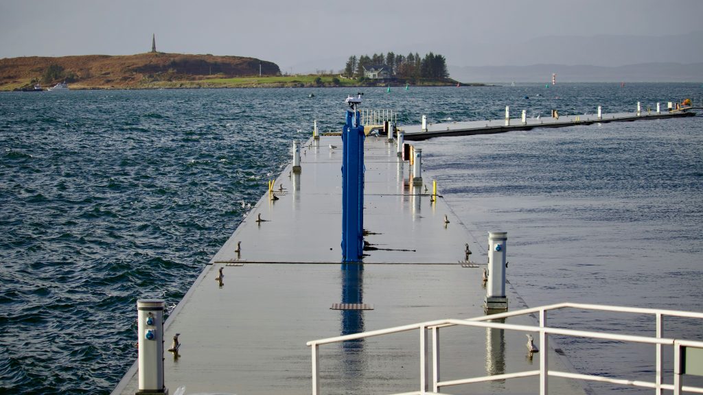 Floating aluminium pontoon walkway with service pedestals in a coastal marina